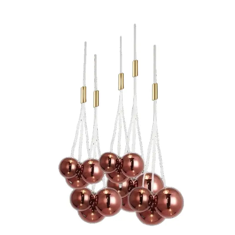 A cluster of rose gold metallic spherical decorbites glass ball chandelier ornaments suspended by white cords with gold connectors