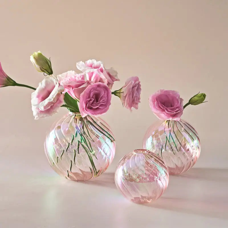 Three iridescent pink glass ball vases with swirling patterns holding pink roses for home decor vase set