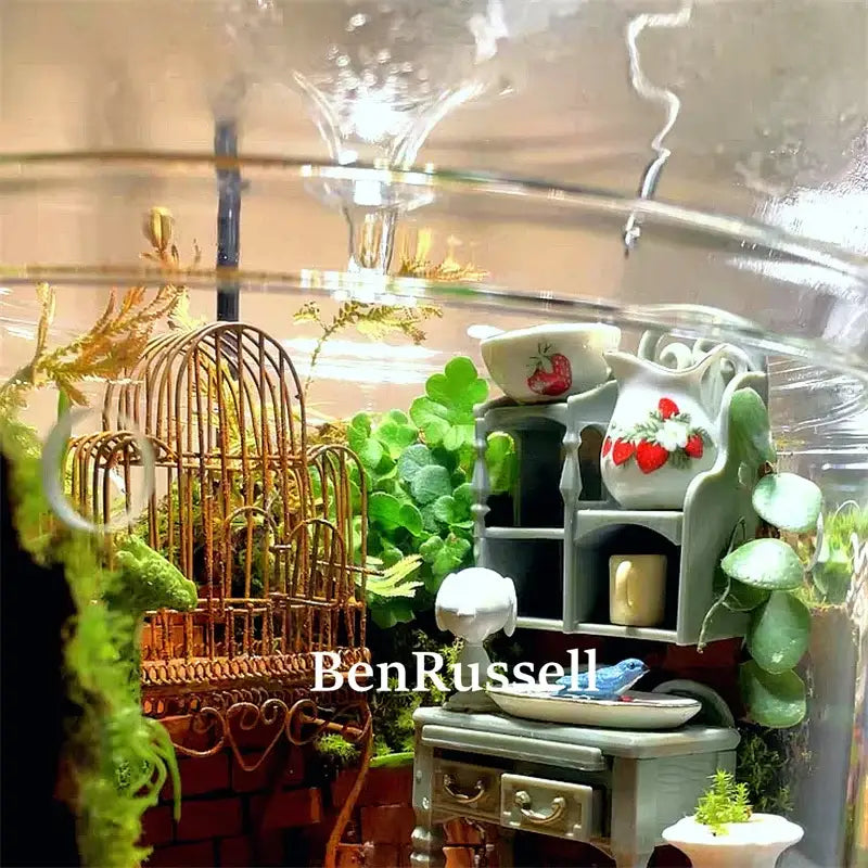 A miniature ceramic pitcher with red strawberry decals on a gray shelf inside a decorbites glass bottle terrarium kit