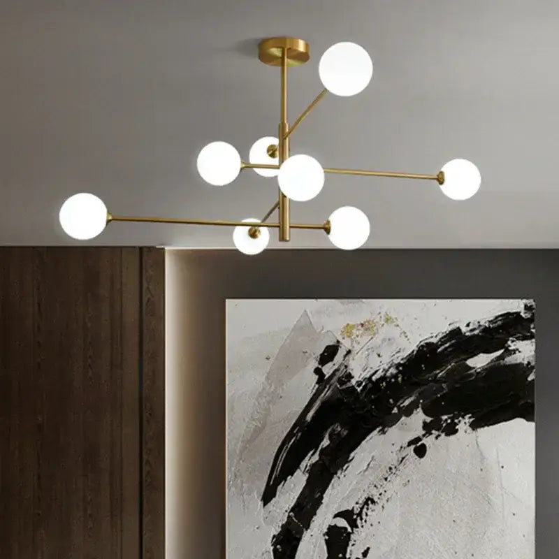 Modern gold-toned decorbites glass brass chandelier with multiple white glass bulbs in geometric branching design for living room