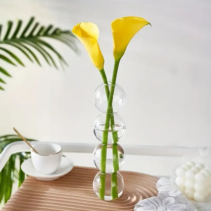 Decorbites glass bubble hydroponic vase with stacked spherical clear glass sections holding two yellow calla lilies