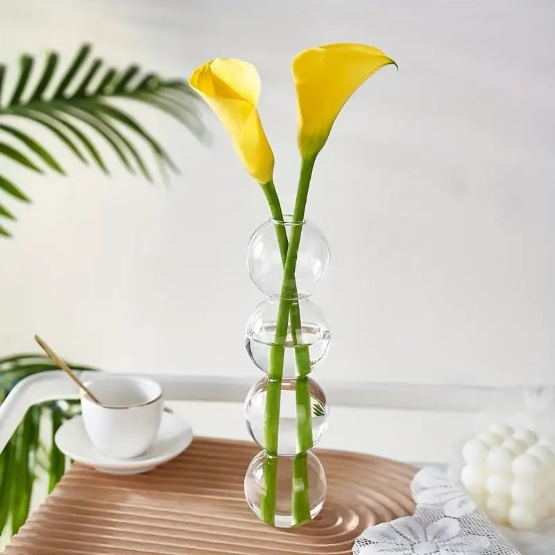 Decorbites glass bubble hydroponic vase with stacked spherical clear glass sections holding two yellow calla lilies