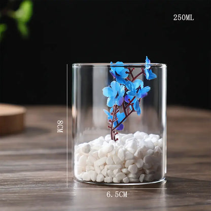 DecorBites glass vase with white pebbles and blue artificial flowers as a stylish planter vase for desktop decor