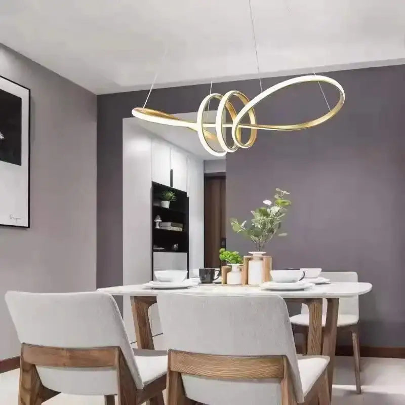Gold-toned glass pendant lights with infinity-loop design and led for modern home decor above dining table