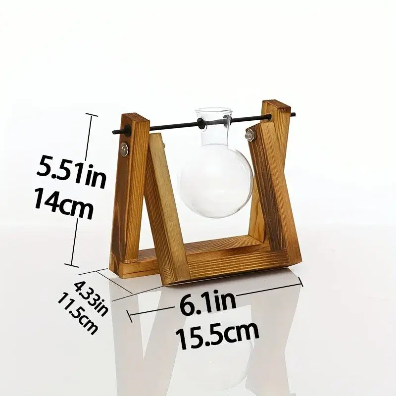 DecorBites glass planter propagation station with clear round-bottomed flask suspended by black rod on wooden rack