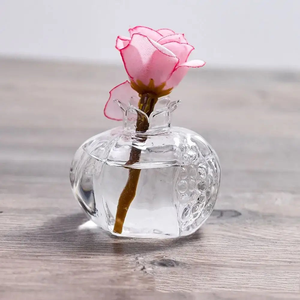 A delicate pink fabric rose with brown stem in a clear textured pomegranate glass vase by decorbites home decor