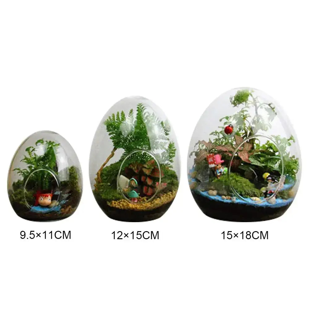 Three high quality glass egg-shaped terrariums by decorbites containing miniature plants and decorative figurines