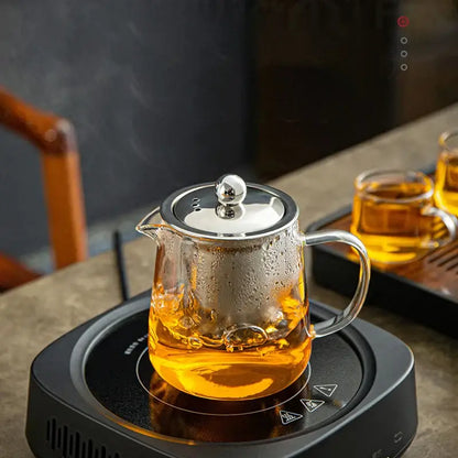 DecorBites™ glass tea jug set with clear glass tea jug filled with amber tea and stainless steel lid and handle
