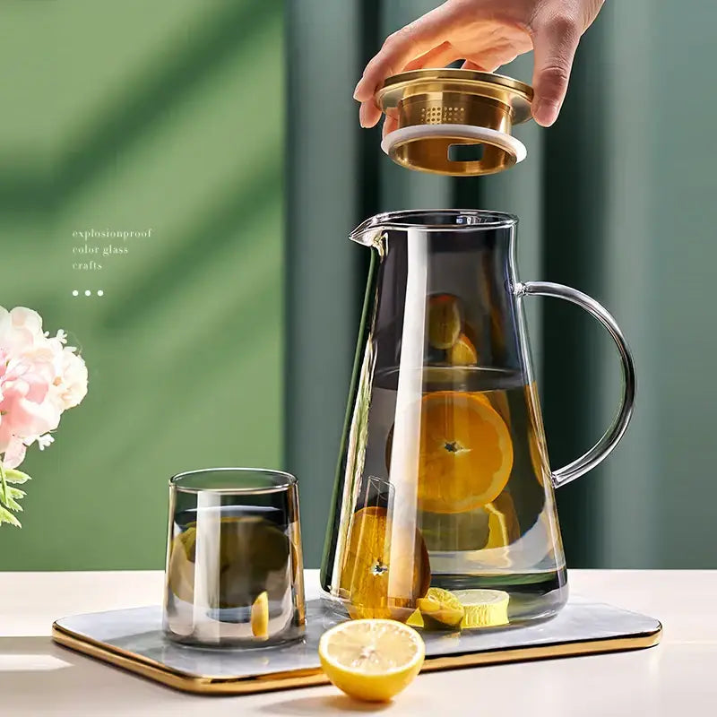 Clear glass tea jug with gold-toned lid and handle filled with citrus water from decorbites water kettle set