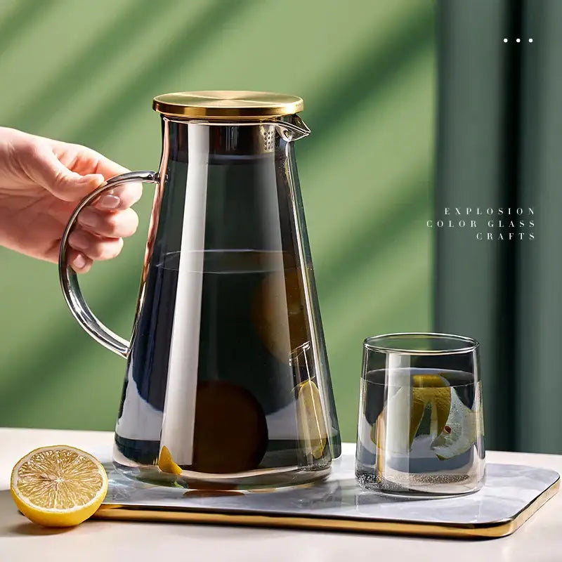 Decorbites glass tea jug with gold lid and handle filled with lemon slices dark liquid in heat resistant water kettle set