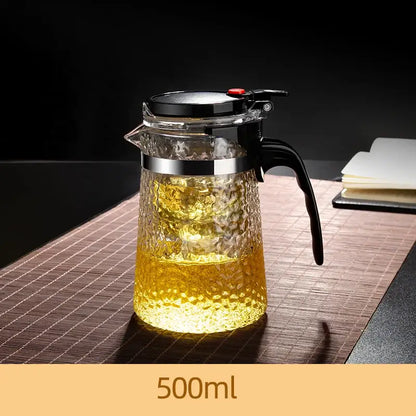 Decorbites glass tea maker with clear textured glass, black handle, silver rim, and black lid with red button for brewing tea