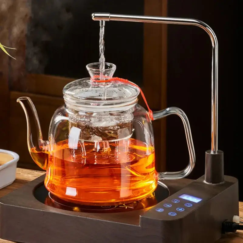 Clear glass tea pot with stainless steel spout and handle filled with amber tea from DecorBites tea pot set