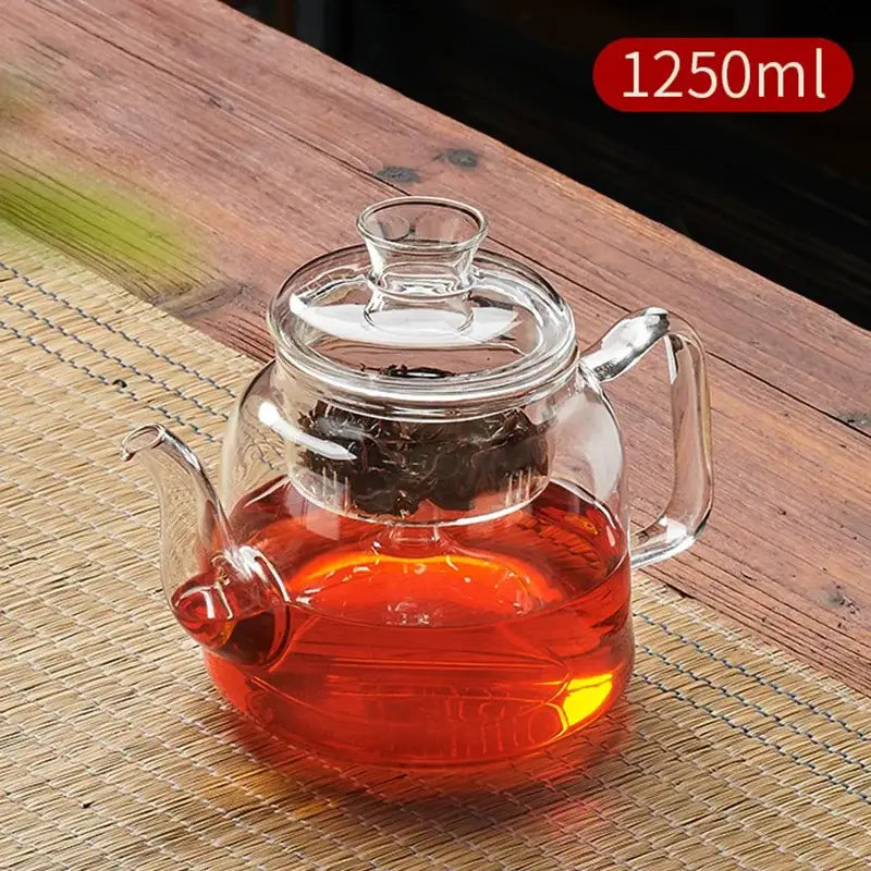 Decorbites™ glass tea pot set featuring a clear glass tea pot with lid and handle filled with amber tea