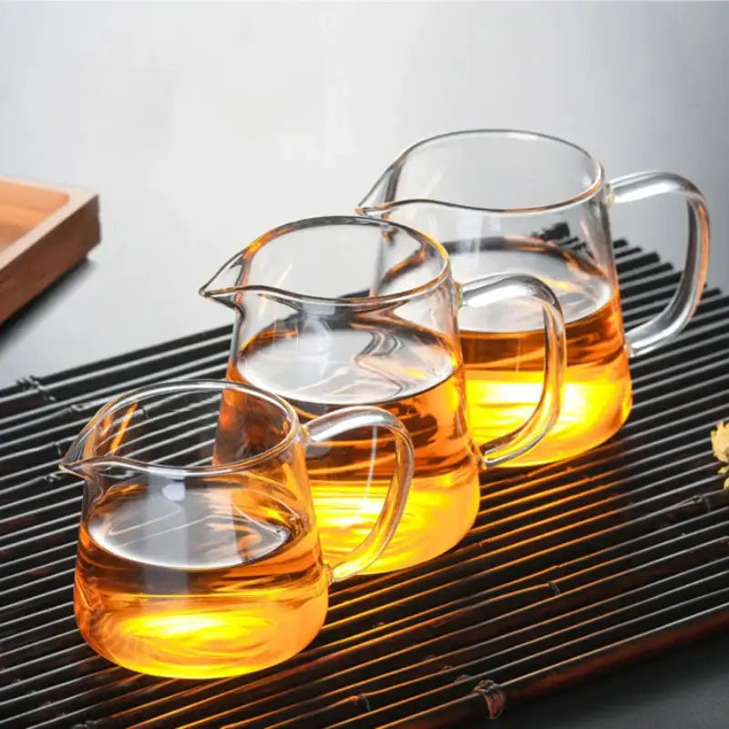 Decorbites glass tea pot set with infuser featuring three clear glass pitchers filled with golden amber tea