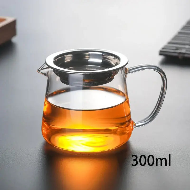 Clear glass tea pot set with stainless steel infuser filled with amber tea for puer tea brewing by DecorBites