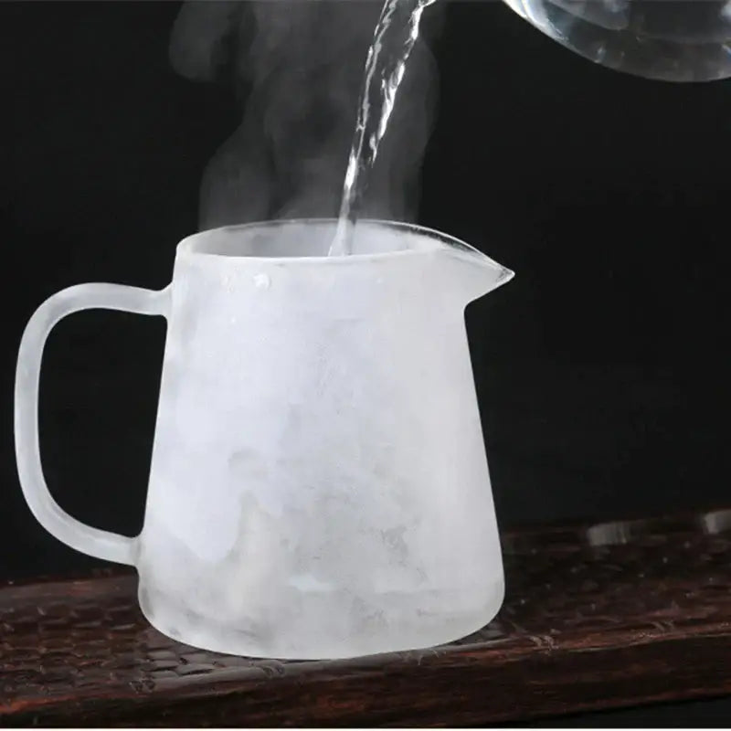 Frosted glass tea pot with handle and spout filled with steaming hot water from the decorbites tea pot set
