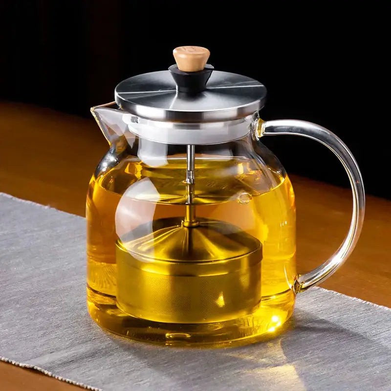 Decorbites glass tea pot with heat-resistant clear glass, stainless steel lid, wooden knob, and built-in metal infuser with golden tea inside