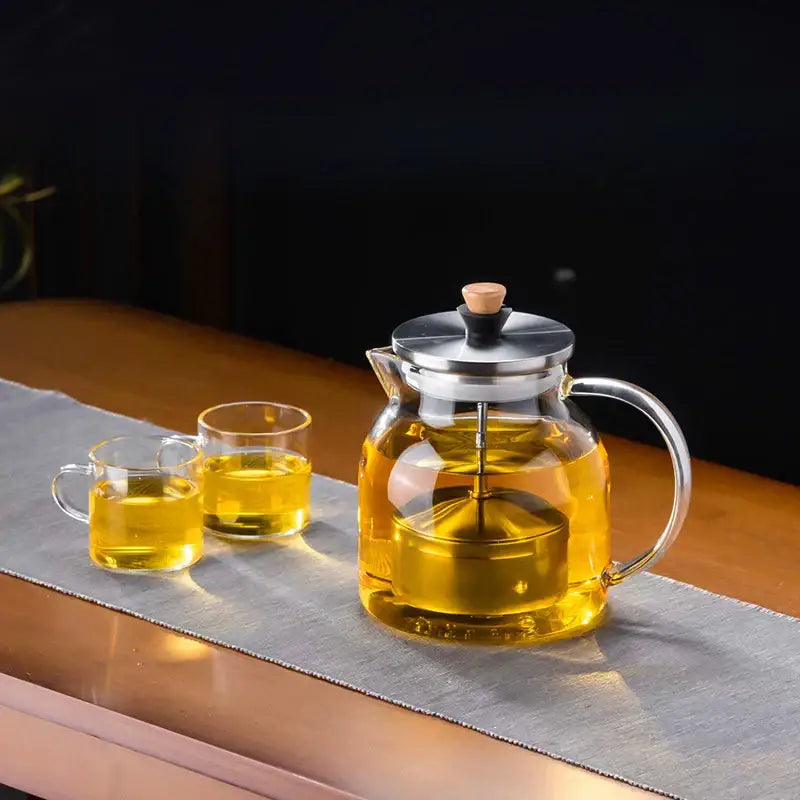 Decorbites glass tea pot with stainless steel lid and handle filled with golden tea for herbal brewing