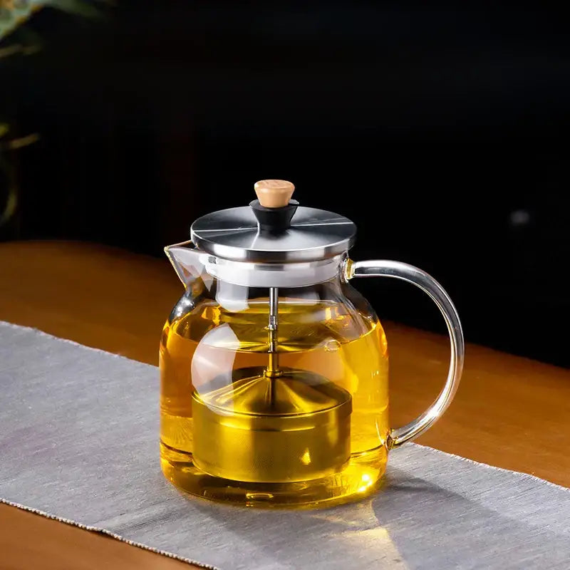 DecorBites glass tea pot with a clear glass body, stainless steel lid and handle, and wooden knob for herbal tea