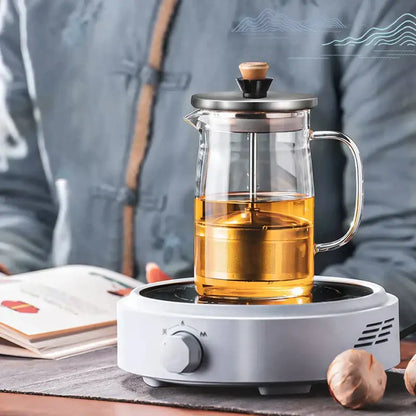 Decorbites glass tea pot with stainless steel lid and wooden knob filled with golden herbal tea