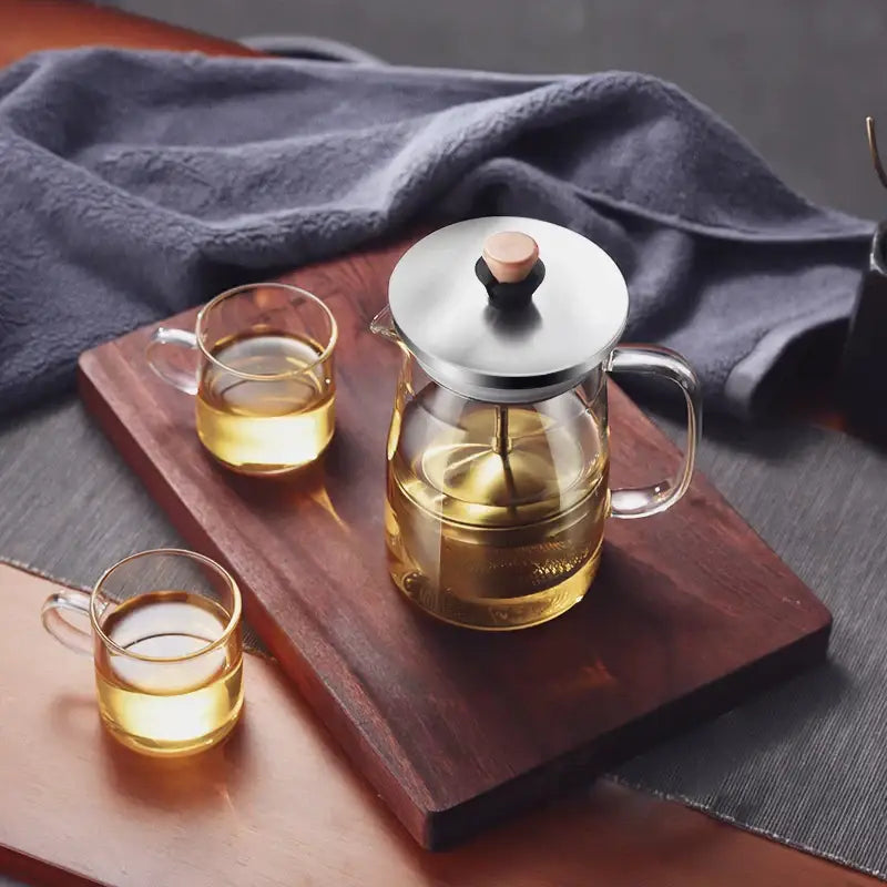 Decorbites glass tea pot with infuser featuring a clear glass body, stainless steel lid, and wooden knob filled with golden tea