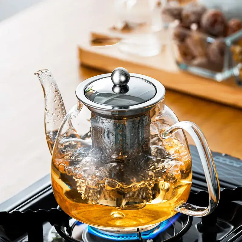 DecorBites glass tea pot with stainless steel filter filled with steaming golden tea for steeping puer coffee and tea