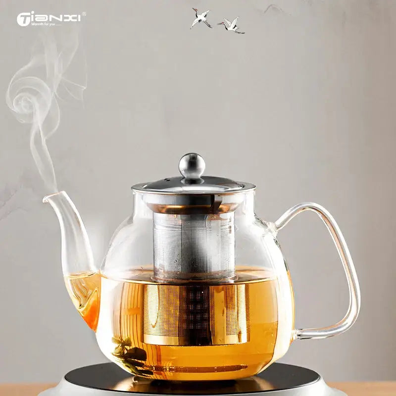 Clear glass tea pot with stainless steel lid and built-in filter filled with steaming golden tea for steeping puer