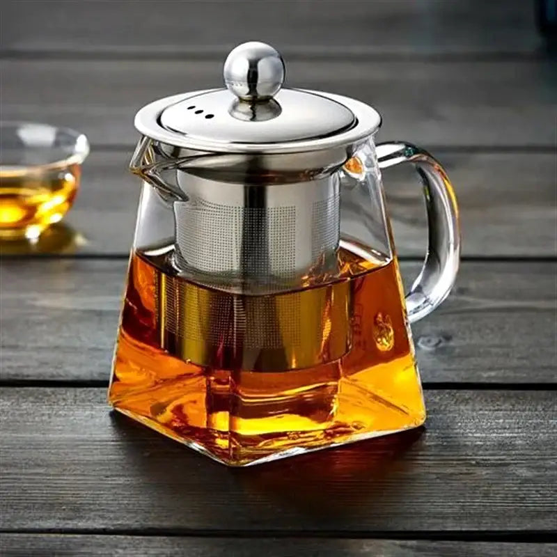 DecorBites glass tea pot with stainless steel lid handle and built-in infuser filled with amber tea