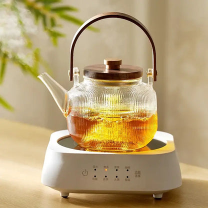 Clear ribbed glass tea pot with wooden lid and handle on white electric heating base from decorbites glass tea set