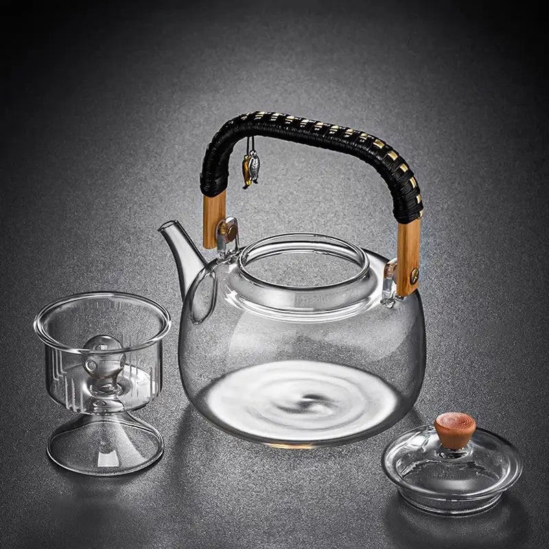 DecorBites glass tea pot with clear heat-resistant glass, black and gold weave handle, wooden accents, and silver charm
