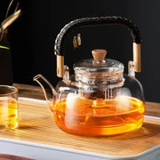 DecorBites glass tea pot with transparent heat-resistant glass, black weave handle, wooden accents, and bamboo lid knob