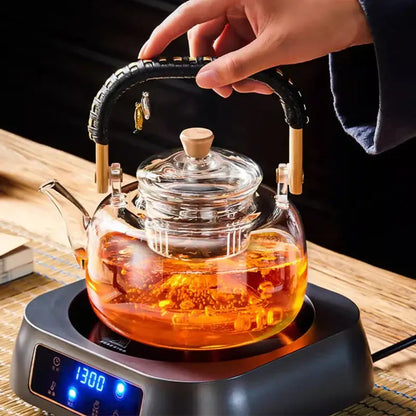 Clear glass decorbites glass tea pot with black weave handle wooden accents filled with amber tea