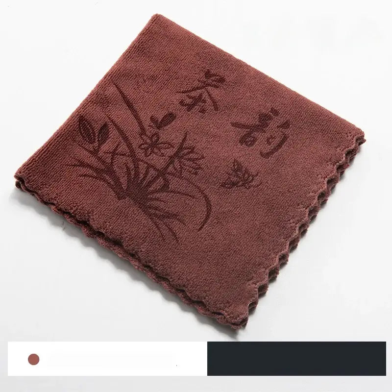 A plush rust-colored tea towel with subtle floral embroidery included with the decorbites glass tea pot wooden handle