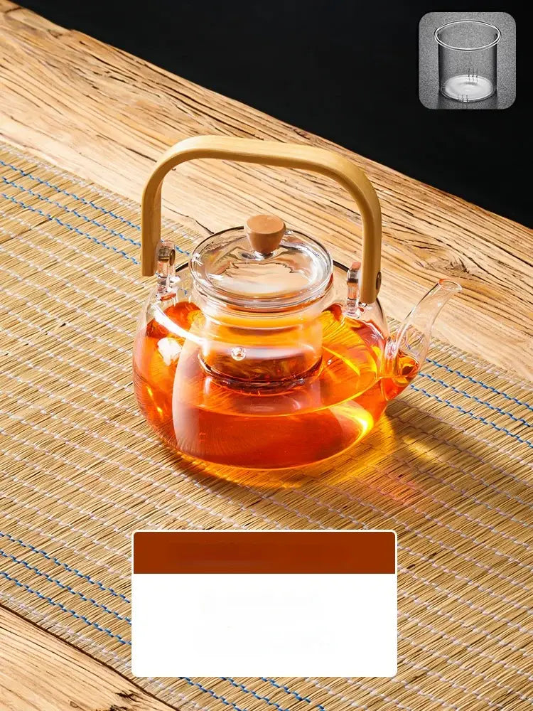 Clear glass tea pot with gold-toned handle and lid knob filled with amber tea by decorbites glass tea with wooden handle