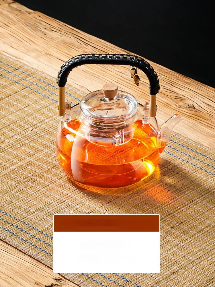 Decorbites glass tea pot with wooden handle clear glass body black woven handle filled with amber tea 900ml capacity