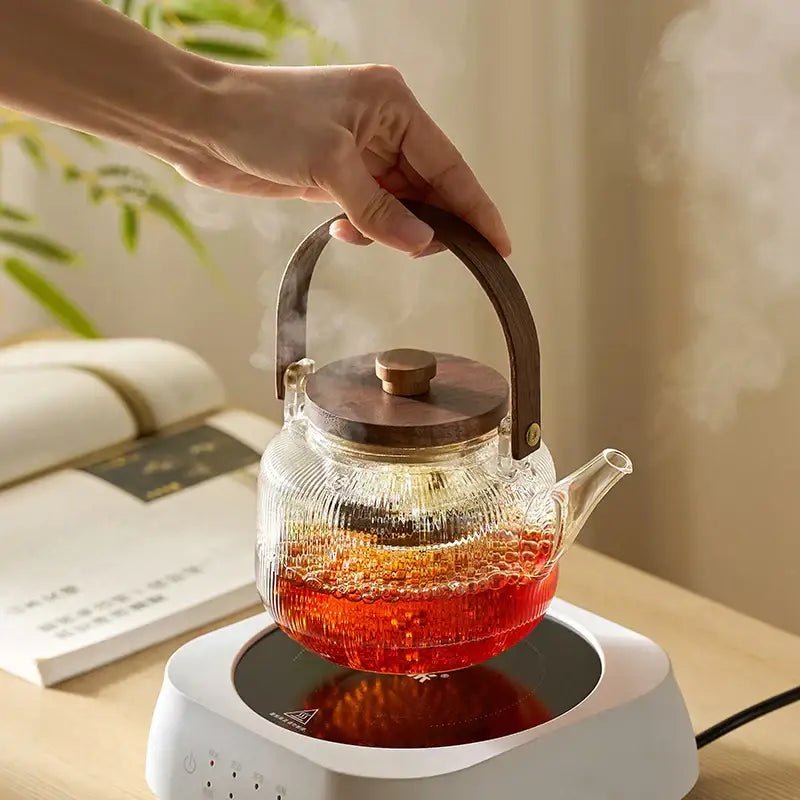 Clear glass tea pot with wooden handle and lid filled with steaming red tea decorbites glass tea pot with filter