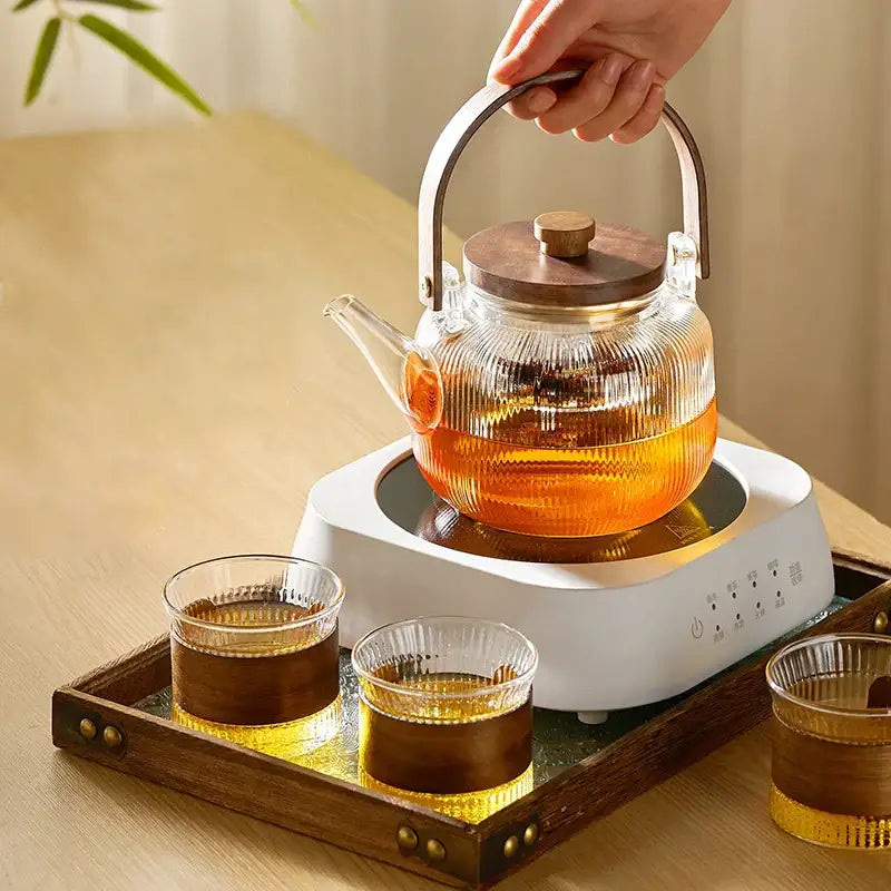 Clear ribbed glass tea pot with wooden handle and lid on electric base from DecorBites glass tea set