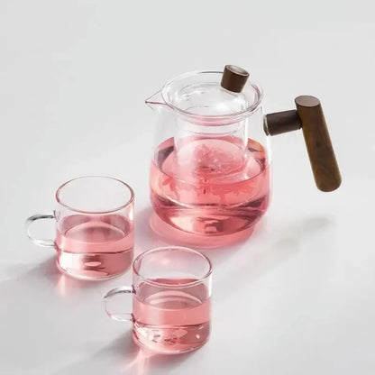 Clear glass tea pot filled with pink tea featuring a dark wood handle and lid knob from decorbites glass tea set
