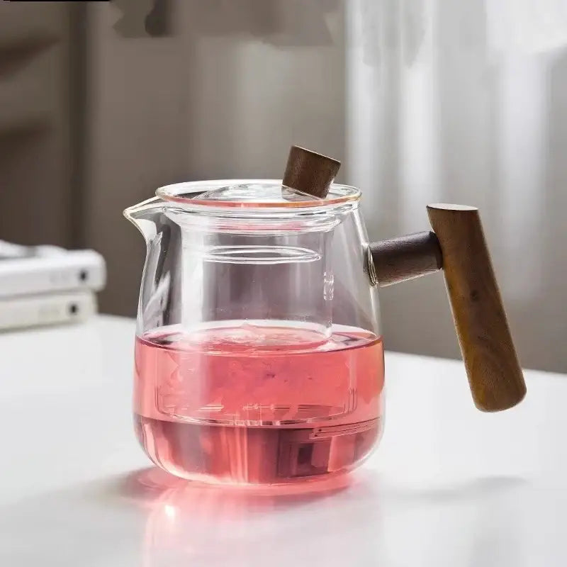 Clear glass tea pot with wooden handle and lid knob filled with pink tea from decorbites glass tea set