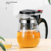 Clear glass tea pitcher with black lid and handle filled with amber brewed tea from decorbites glass tea set