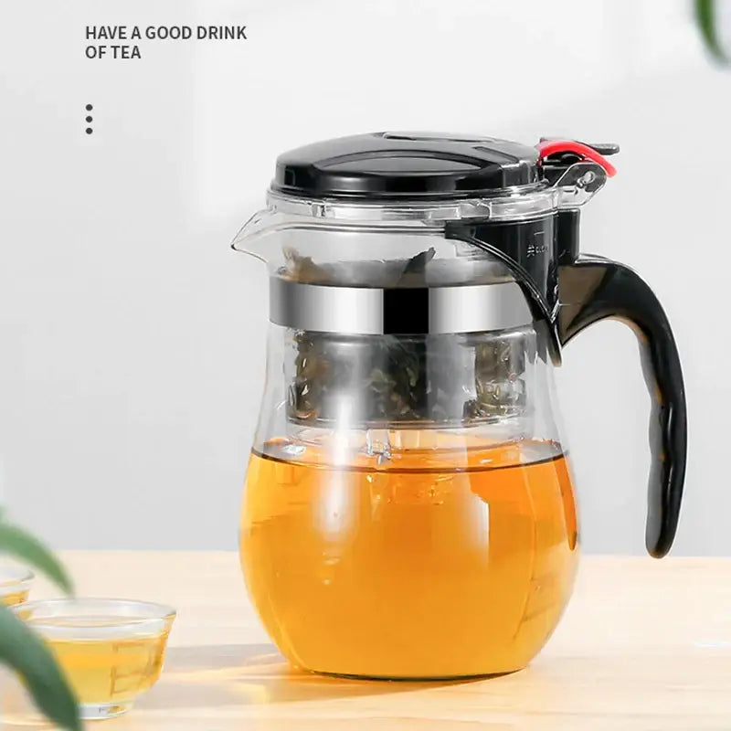 Clear glass tea pitcher with black lid and handle filled with amber brewed tea from decorbites glass tea set