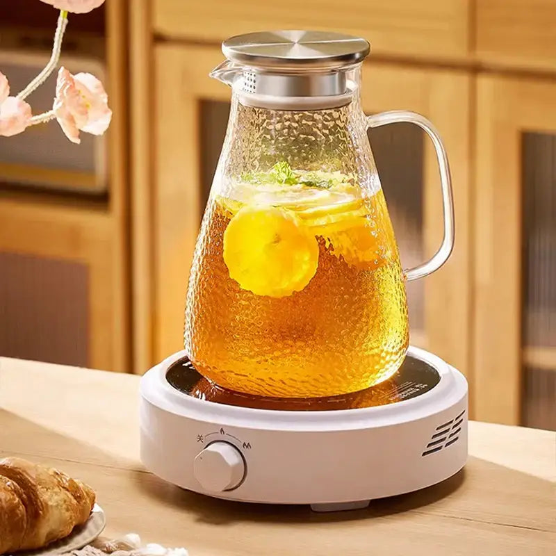 Clear textured glass pitcher with stainless steel lid and handle filled with golden tea and lemon slices in decorbites glass tea set