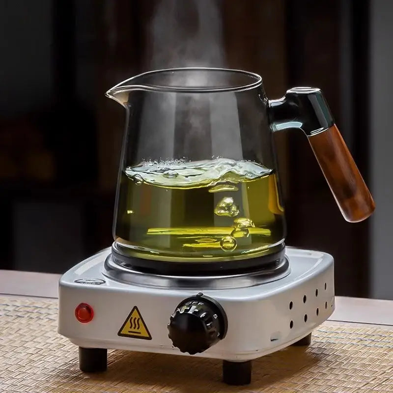 Clear glass teapot with wooden handle on white electric base part of decorbites™ tea set with retro glass tray