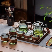 Clear glass tea set with wooden handle teapot and matching glasses on a retro glass tray by DecorBites