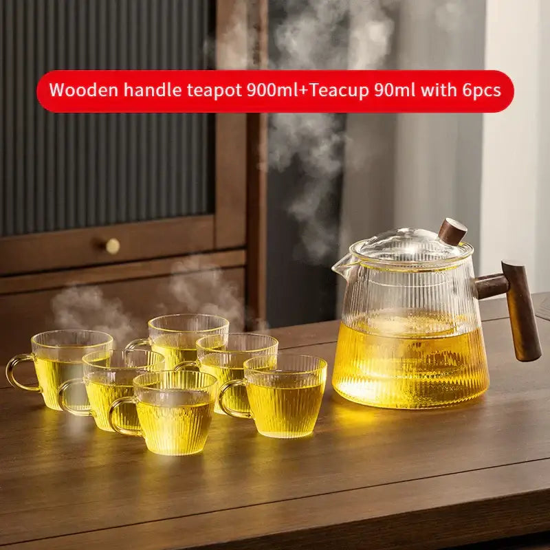 Clear decorbites glass teapot with wooden handle filled with steaming golden tea for puer kung fu tea brewing