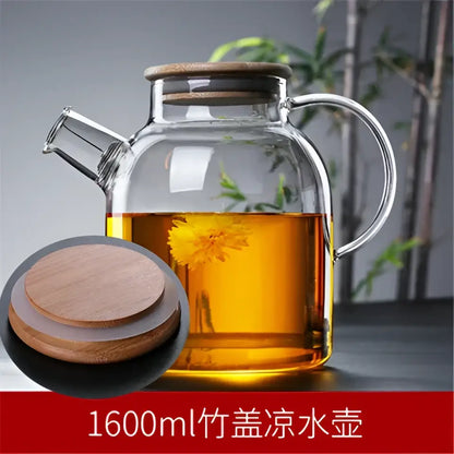 Decorbites glass teapot with bamboo lid and handle filled with golden tea and floating yellow flowers for cold water use