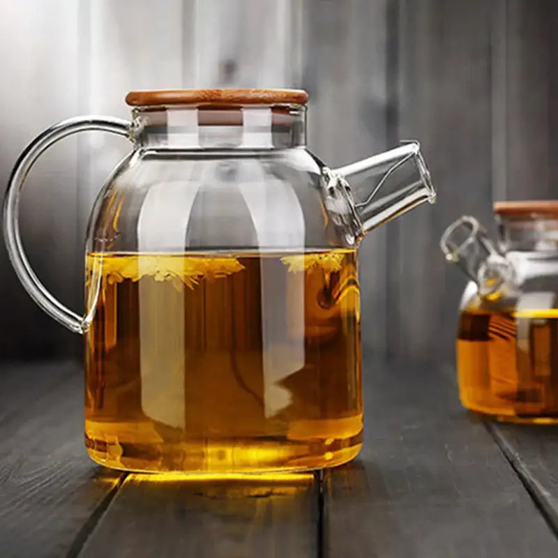 Clear DecorBites glass teapot cold with wooden lid and handle filled with golden tea for large capacity use