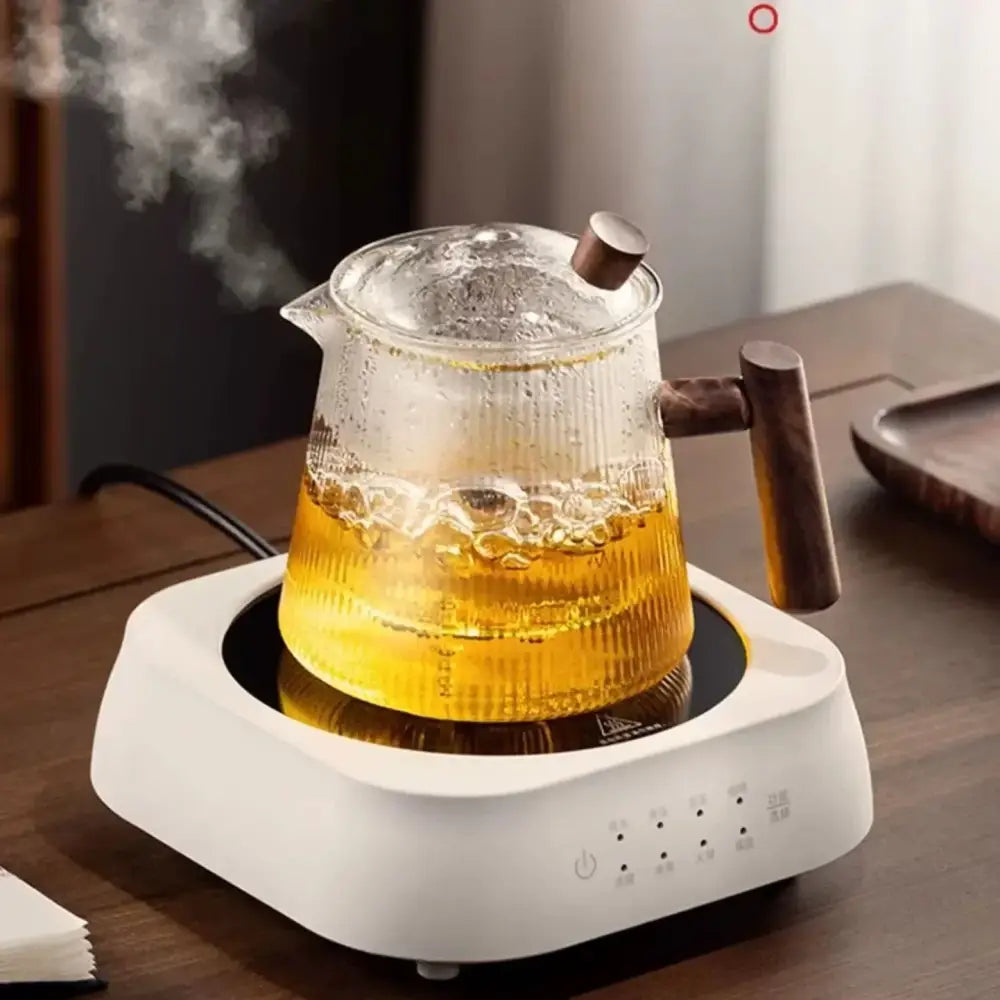 A clear decorbites glass teapot with wooden handle filled with steaming golden tea made of high borosilicate material
