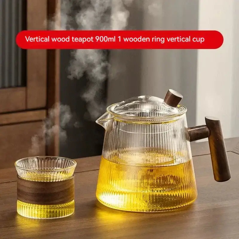Vertical decorbites glass teapot with dark wood handle and lid filled with steaming golden tea made of high borosilicate