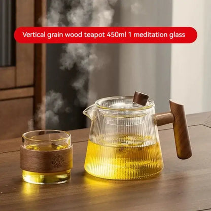 Clear glass decorbites glass teapot with vertical wood grain handle and lid knob filled with steaming golden tea
